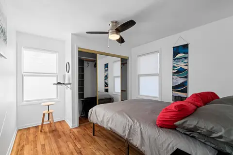 Queen bedroom with red pillows, a wall-mounted desk, and a mirrored closet