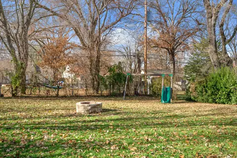 Backyard lawn with the fire pit and a swing set along the tree line