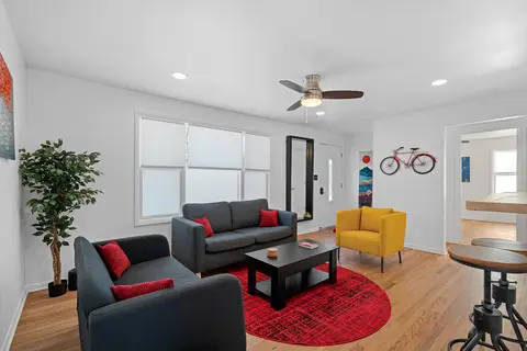 Living room with a gray sofa, a yellow armchair, a red rug, and a red bike on the wall