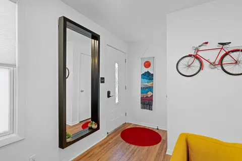 Entryway with a full-length mirror, a red rug, and a red bike on the wall