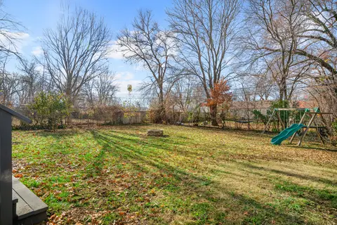 Wide backyard lawn with the fire pit and the swing set