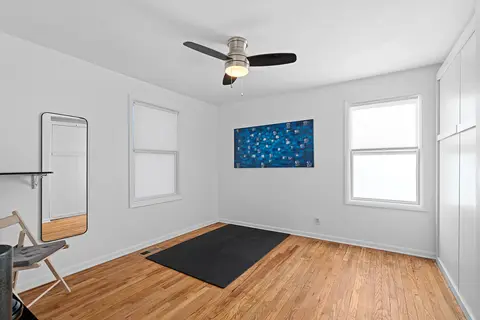 Bedroom with a blue painting, a floor mirror, a folding chair, and an exercise mat