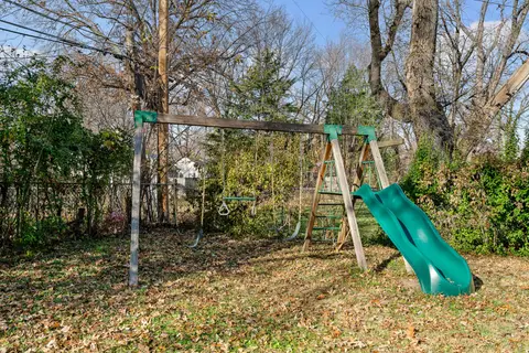 Swing set with a green slide at the edge of the yard