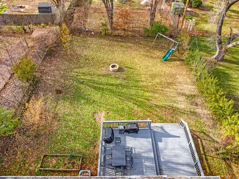 Overhead view of the deck and the lawn, with the fire pit and swing set beyond