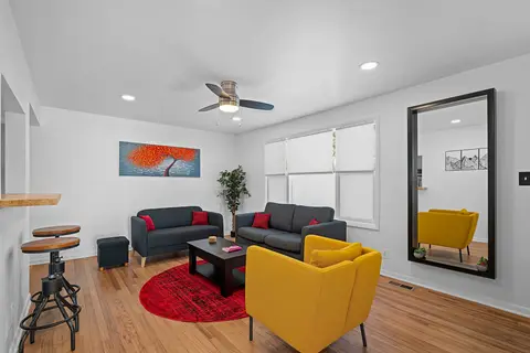 Living room with sofas, a yellow armchair, a red rug, and a tall mirror
