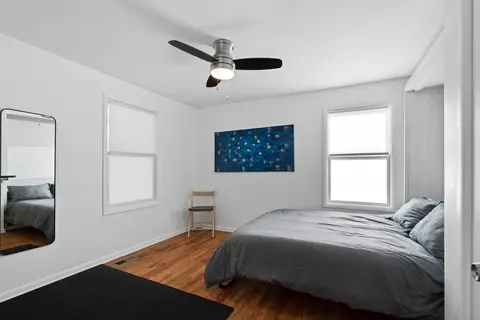 Queen bedroom with gray bedding, a blue painting, and a full-length mirror