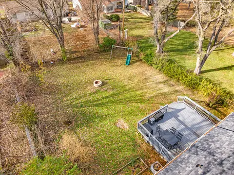 Overhead view of the backyard, with the deck, the fire pit, and a swing set on the lawn