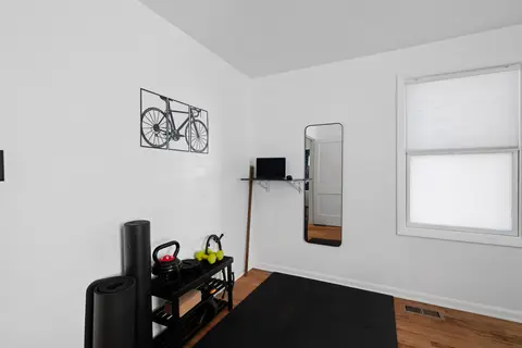 Wall-mounted desk with a laptop and a floor mirror, next to the workout gear