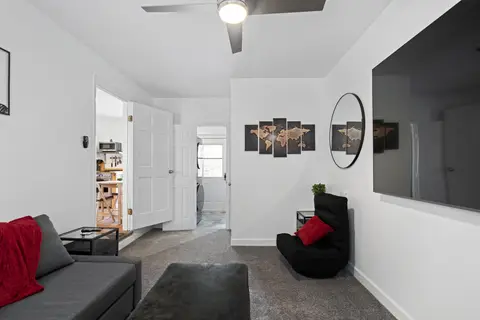 Den with a lounge chair, a round mirror, and a door through to the kitchen