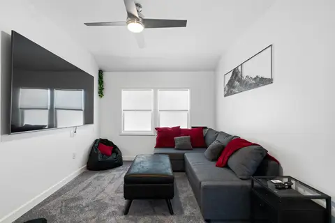 Gray sectional and storage ottoman facing a large wall-mounted TV