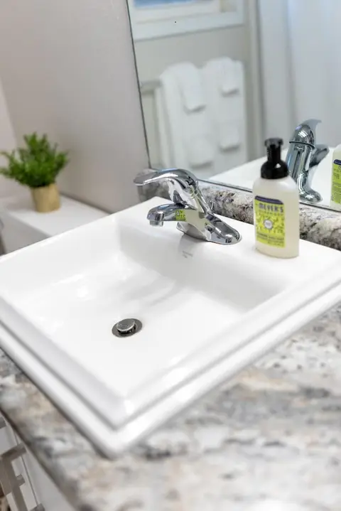 White bathroom sink with a chrome faucet and hand soap
