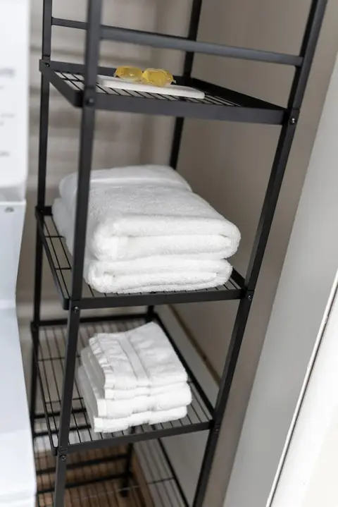 Folded white towels on a black metal shelf