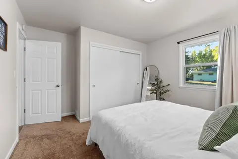 Bedroom with a queen bed, a white closet, and a window