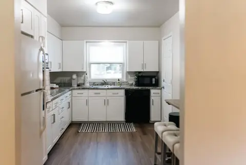 Kitchen with white cabinets, a white refrigerator, and stools at the counter