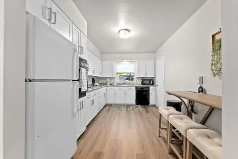 Kitchen with white cabinets, a white refrigerator, and a counter with stools