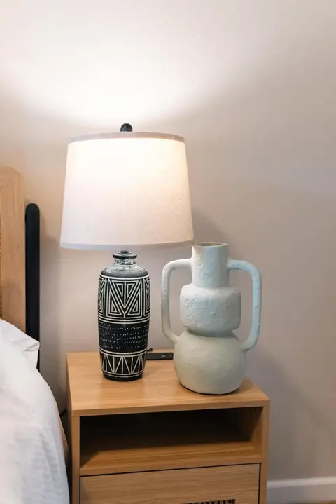 Patterned table lamp and a white vase on a nightstand