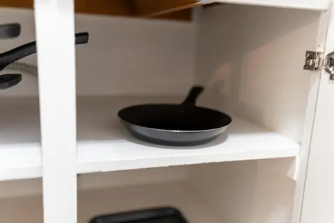 Frying pan on a cabinet shelf