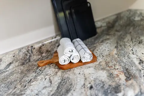 Rolled dish towels on a wood board on the granite counter