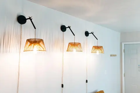 Three black wall sconces with woven shades