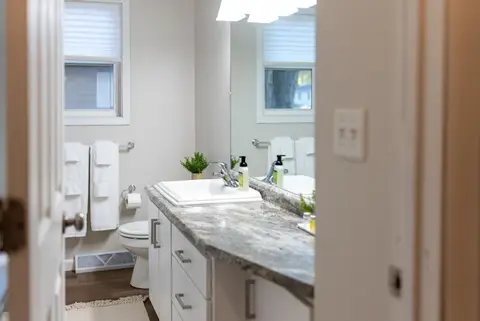 Bathroom with a granite vanity, a toilet, and towels on wall hooks