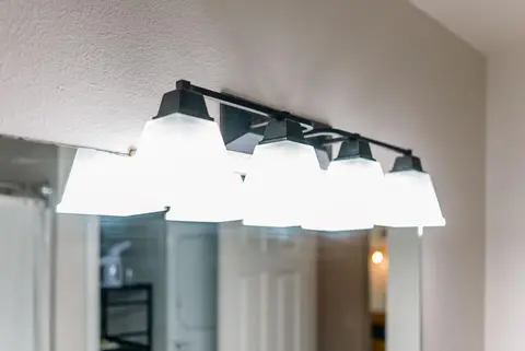 Black vanity light with white glass shades over the bathroom mirror