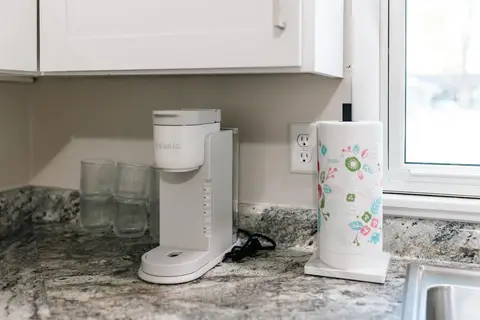 Single-serve coffee maker, glasses, and a paper towel holder on the counter