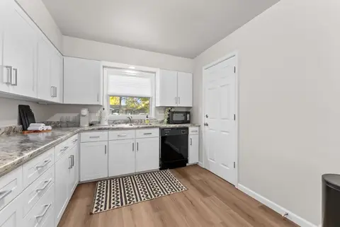 Kitchen counters wrapping around to a black dishwasher and a white door