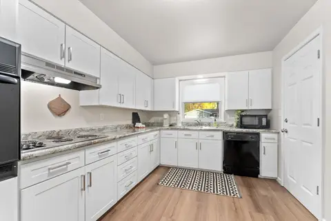 Kitchen with white cabinets, granite counters, and a black dishwasher