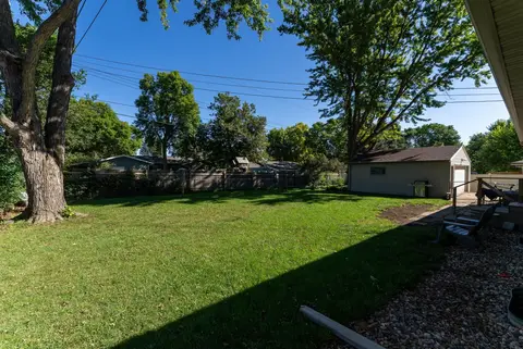Fenced backyard with a lawn, shade trees, and a detached garage