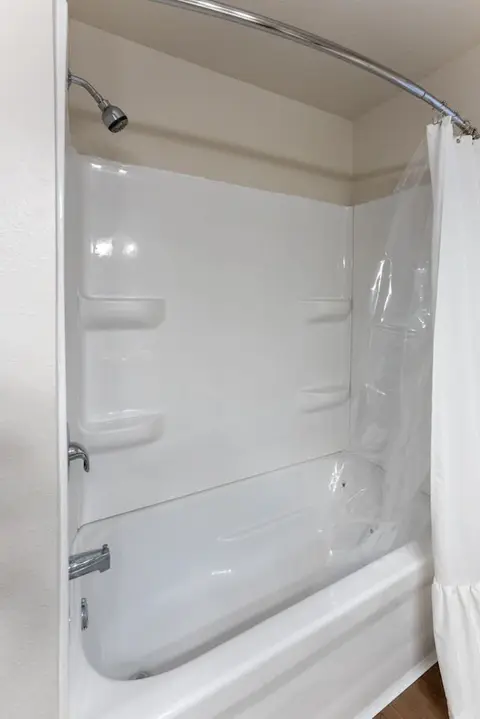 White tub and shower surround with built-in shelves