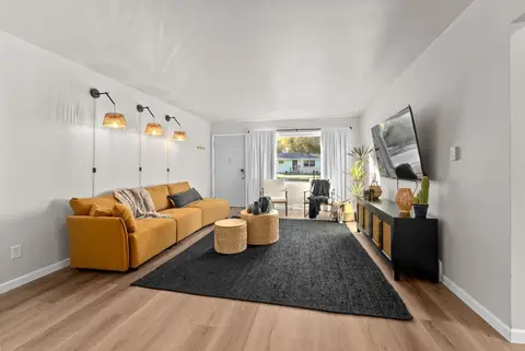 Mustard sofa under three wall sconces, with a TV across the room