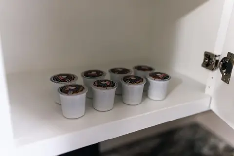 Coffee pods lined up on a cabinet shelf