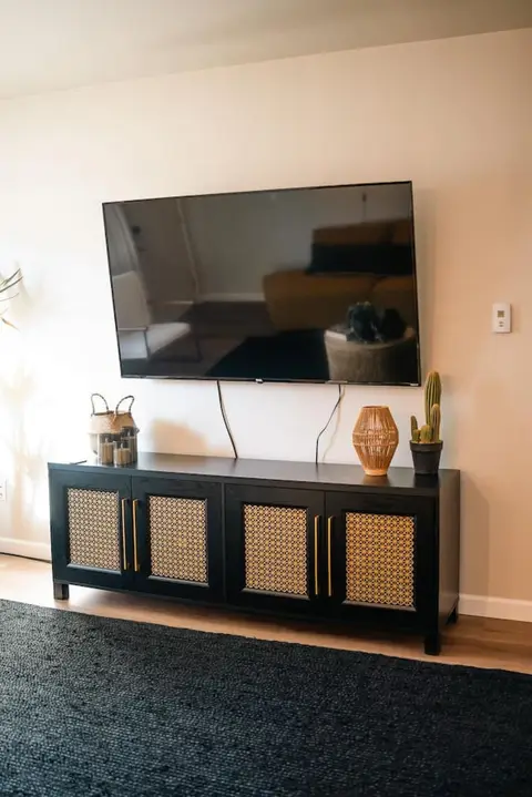Wall-mounted TV above a black and rattan console