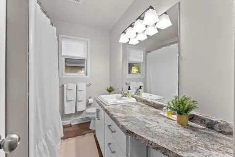 Bathroom vanity with a granite counter, a long mirror, and white towels