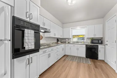 Kitchen with a black wall oven, white cabinets, and a patterned rug