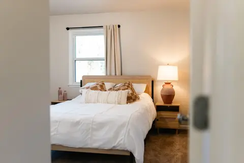 Queen bed with a rattan headboard and a table lamp, seen from the doorway