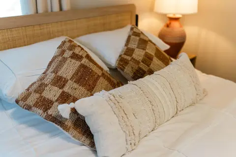 Checked and cream throw pillows on a white queen bed