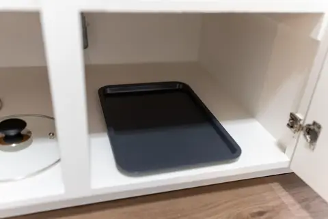 Baking sheet and a pot lid in a lower cabinet