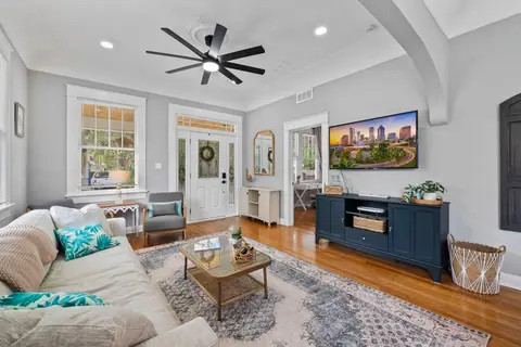 Living room with a cream sofa, a glass coffee table, and a wall-mounted TV