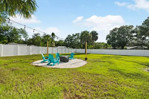 Fire pit with four teal Adirondack chairs under string lights