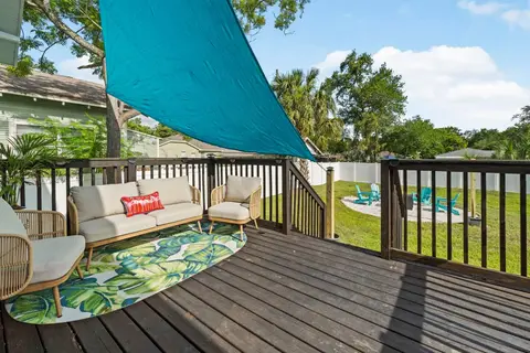 Back deck with an outdoor sofa and chairs under a teal shade sail