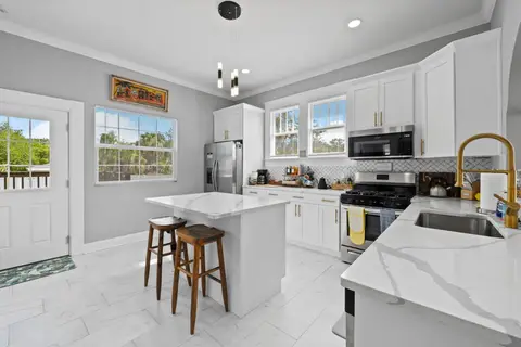 Kitchen island with two stools, a gold faucet, and a door to the back deck