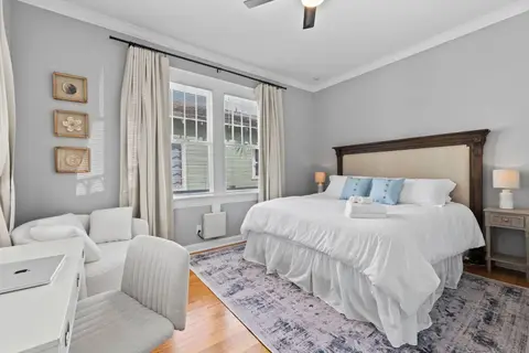 King bed with an upholstered headboard and an armchair by the windows