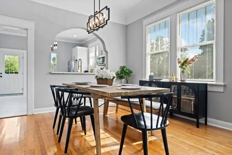 Dining table by tall windows, with a pass-through to the kitchen
