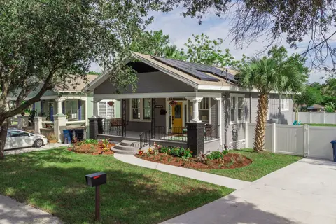 Gray bungalow with a covered front porch, a yellow door, and a fenced side yard