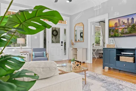 Living room with a glass coffee table, a TV console, and an arched mirror