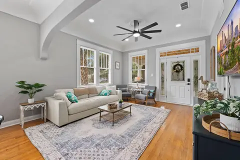 Living room with a cream sofa, two armchairs, and a stained-glass front door