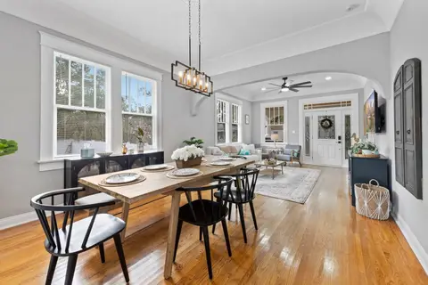 Dining table with black chairs under a pendant light, open to the living room