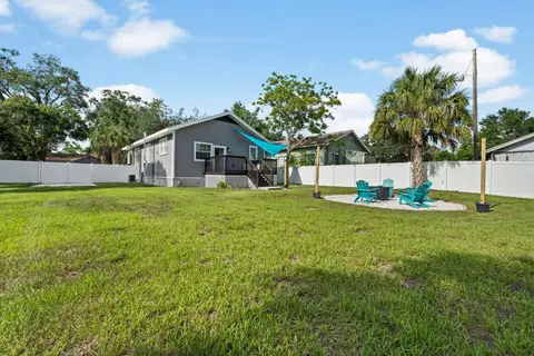Large fenced lawn with the fire pit, looking back to the house and deck