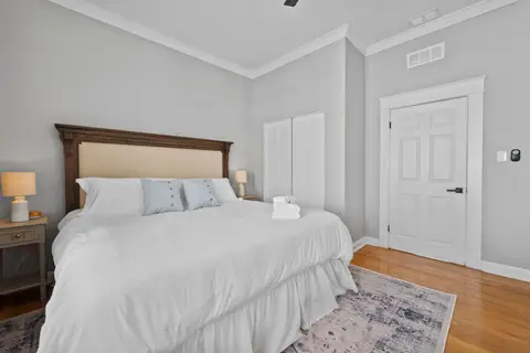 King bed with nightstands and lamps, beside a closet